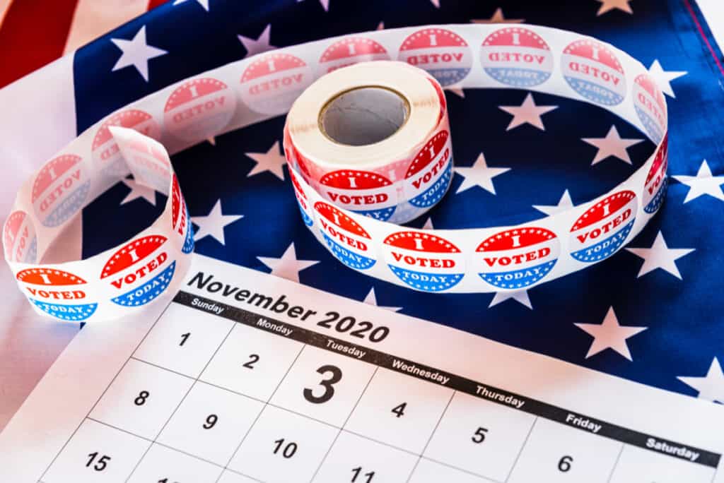 I Voted stickers on American flag, with calendar of November and election day circled