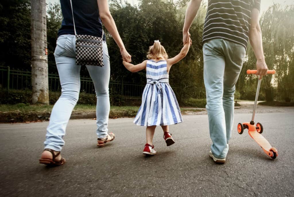 parents walking with little girl in between them, holding hands