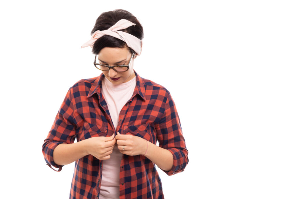 woman buttoning red plaid shirt, wondering if god is good