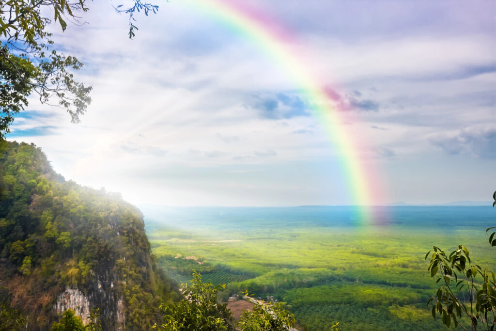 rainbow in blue sky over beautiful landscape.